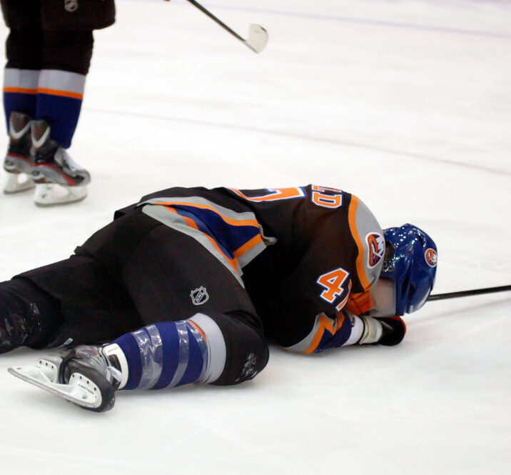 Hockey player lays on the ice after experiencing a concussion