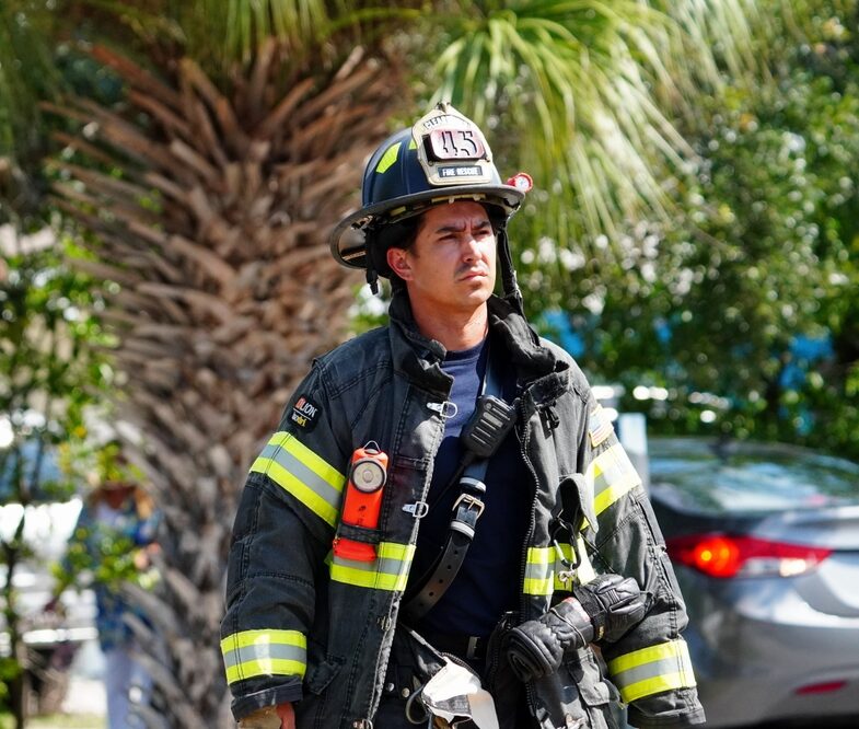 A firefighter walks through a palm tree-lined street