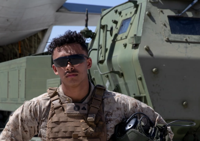 Man in the military stands in front of an army tank