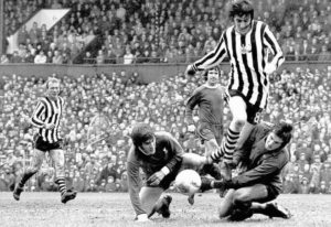 Former professional soccer player John Tudor dives for a ball on the field