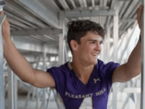 Legacy Donor Wyatt Bramwell in uniform under the football bleachers