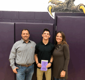 Legacy Donor Wyatt Bramwell and parents smile in the school gymnasium