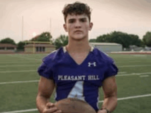 Legacy Donor Wyatt Bramwell holding a football on the field