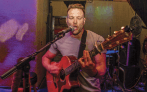 Former NFL player and Legacy Donor Devon Wylie sings while playing the guitar