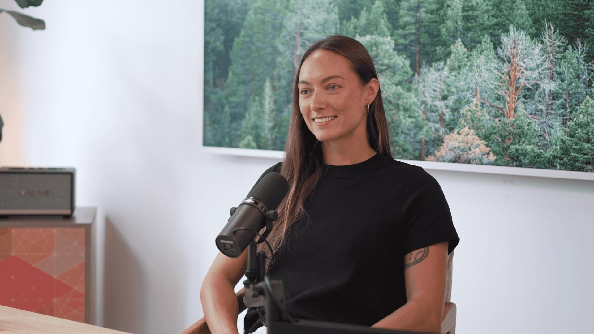 Poet, surfer, and model Kyla Jamieson speaks in front of a microphone for the Invisible Impact podcast