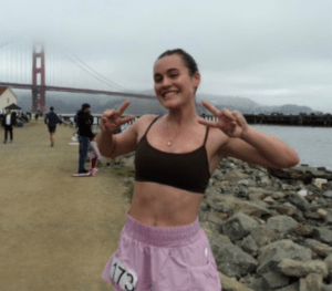 Former soccer player Caroline Souza smiles in front of the Golden Gate Bridge