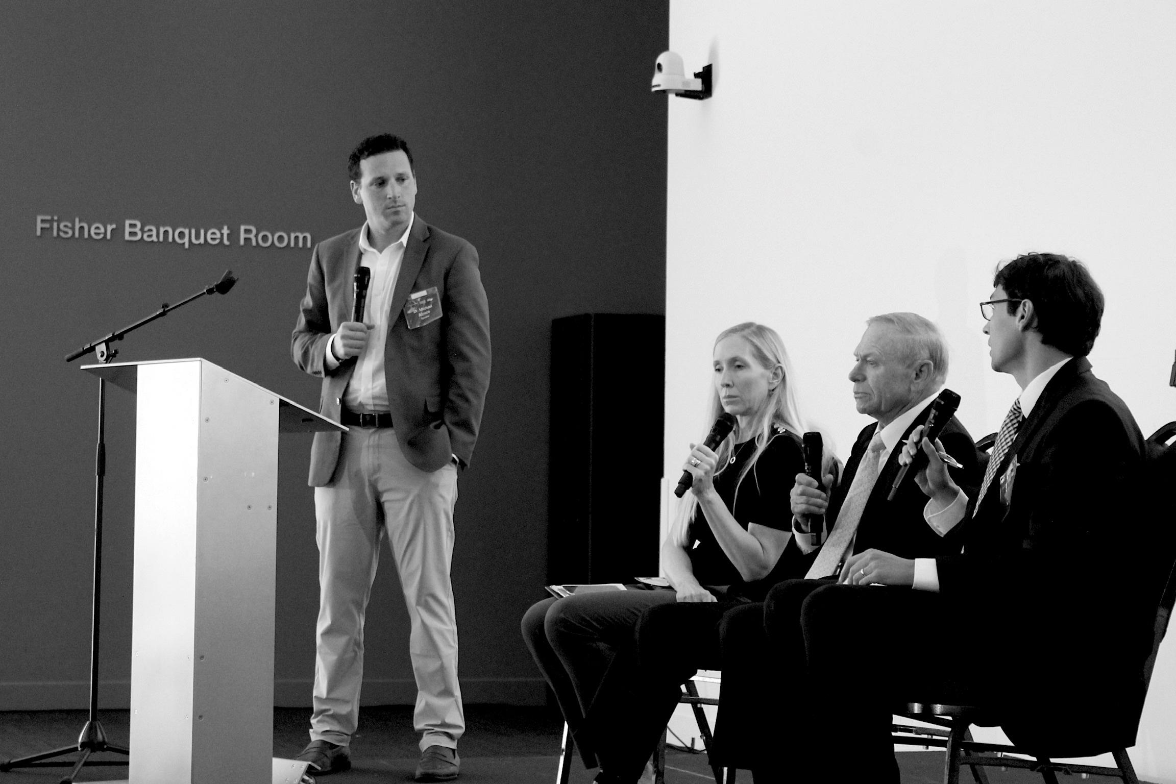 Speaker at a podium along with panelists